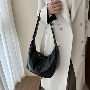 Close-up of a minimalist black hobo bag in soft PU leather with wide shoulder strap
