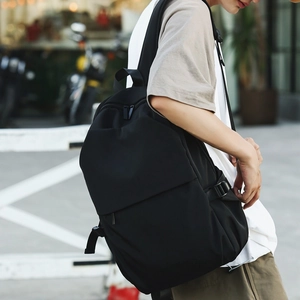 Street view of a black nylon minimalist backpack with adjustable side straps and clean design