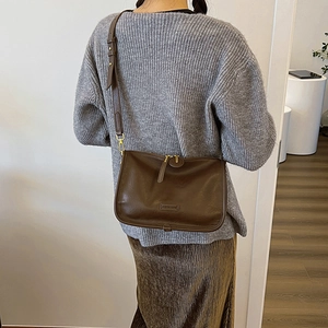 Detail of a brown leather crossbody bag with adjustable strap and double zipper closure