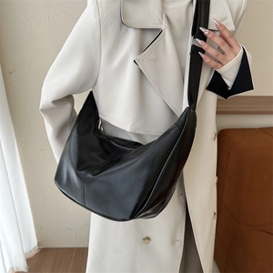Detail view of black moon shaped PU leather crossbody bag with wide shoulder strap