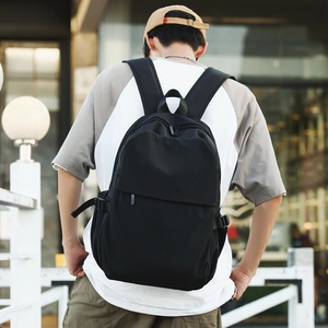 Rear view of minimalist black nylon backpack showing actual size and fit on model back