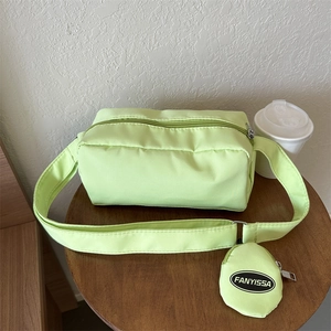 Detail view of a light green nylon crossbody bag with a round coin purse and wide strap