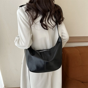 Close-up of black PU leather hobo bag with smooth curved design and metallic zipper detail