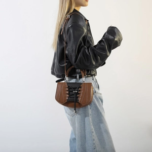 Close-up of saddle-shaped crossbody bag with unique black criss-cross lace detail