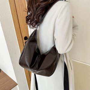 Detail view of the brown leather hobo bag's soft texture and elegant curved shape