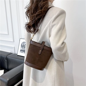 Detail of dark brown bucket bag in matte and smooth leather on a grey blazer outfit