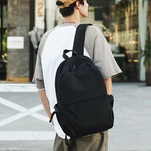 Minimalist black nylon backpack on female model shown in an urban street scene