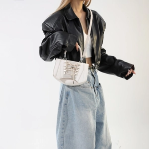 Street style shot of a cream mini handbag with vest-style cross straps and mesh detail