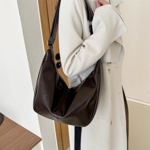 Minimalist dark brown half-moon PU leather crossbody bag worn with a white trench coat
