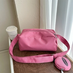 Pink nylon camera bag detail featuring a matching wide strap and round coin purse attachment