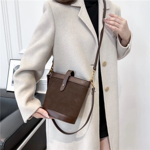 Detail view of a vintage brown PU bucket bag with suede patchwork and adjustable strap