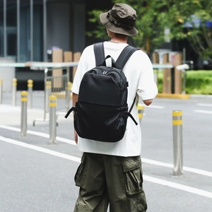 Urban outdoor lifestyle shot of a minimalist black nylon backpack on a model back