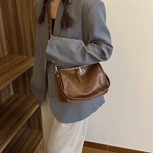 Deep brown vintage PU crossbody bag with golden zippers shown on a grey blazer outfit