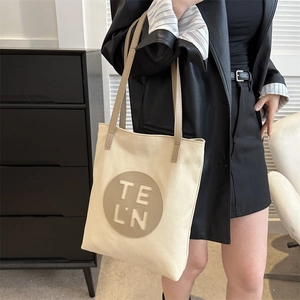 Close-up of minimalist beige canvas tote bag with circular leather logo patch