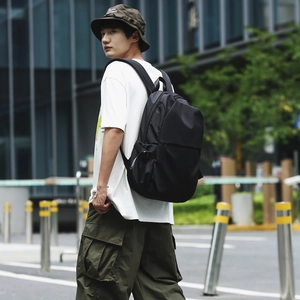 Detail view of the black nylon backpack with wide padded straps and functional side buckles