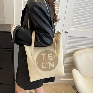Canvas tote bag with leather handles and TELN logo patch shown in a lifestyle setting