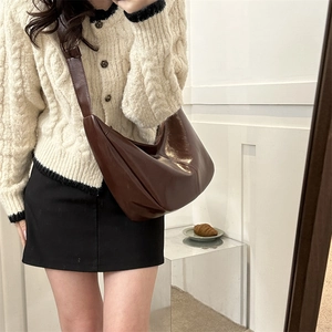 Detail view of dark brown PU leather crossbody bag worn over a beige knit sweater
