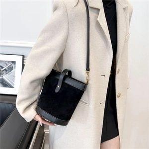 Close-up of minimalist black bucket bag in premium matte PU leather on a fashion model