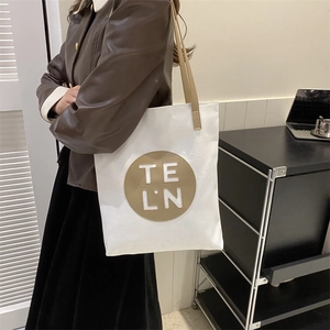 Close-up of minimalist canvas tote bag with brown straps and TE LN leather patch detail