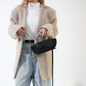 Close-up of matte black leather bag with distinctive silver wavy metal handle detail