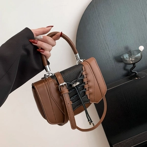 Close-up of a brown leather handbag featuring black grid patterns and silver metal hardware