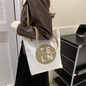 Detail view of large canvas tote bag with contrast shoulder strap and round logo patch