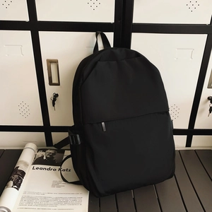 Minimalist black nylon backpack with decorative zipper detail on white cabinet background