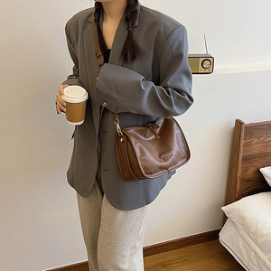 Detailed side view of vintage brown PU leather crossbody bag worn by a model in a room