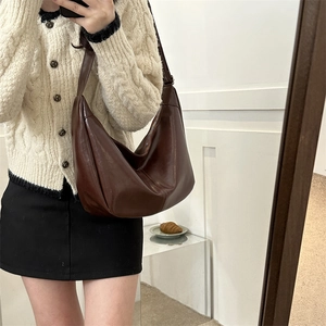 Close-up of a crescent-shaped dark brown PU leather crossbody bag with pleated detail