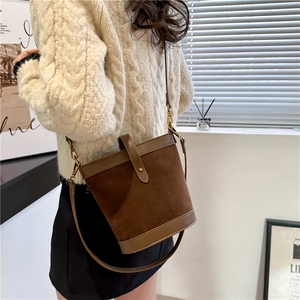 Detail view of a vintage brown suede bucket bag with leather straps and metal hooks