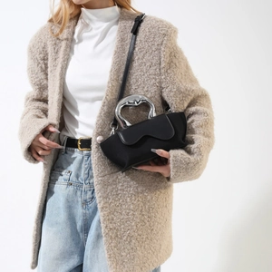 Close-up of a black handbag featuring a unique silver wavy metal handle and matte finish