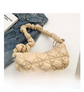 Detail of beige quilted crescent bag with a scrunchie strap and metal zipper closure