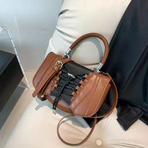 Detail of caramel leather handbag featuring corset-style lace-up design and mesh paneling