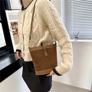 Detail of dark brown suede bucket bag with retro gold buckle on a crossbody strap