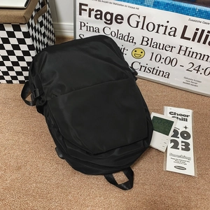 Detailed view of black nylon backpack with front pocket and side buckles on a woven rug
