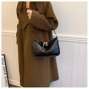 Detail of minimalist black PU leather crescent hobo bag with gold hardware on a model
