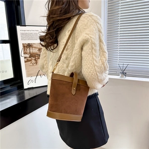 Close-up of vintage brown bucket bag with gold buckle on a model in white sweater