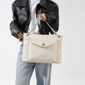 Détail du sac fourre-tout en cuir verni blanc cassé avec chaîne argentée et fermoir rotatif