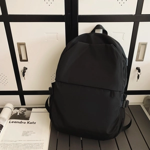 Detail view of the black nylon backpack showing zippers, storage layers, and side buckles