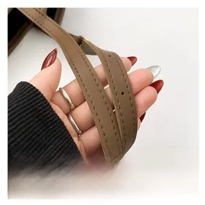 Detail of brown leather bag strap with precision stitching and adjustable buckle holes