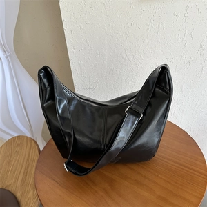 Top-down view of a black PU hobo bag with adjustable strap on a wooden display