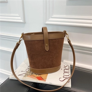 Detail of vintage brown bucket bag with mixed textures on a magazine background