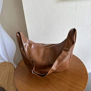 Detail of a brown PU leather Hobo bag with silver buckle on a wooden display
