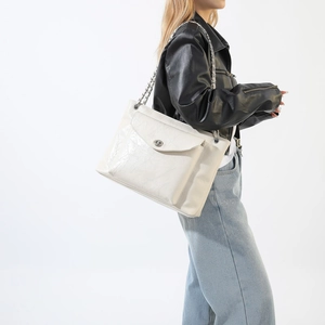 Détail du sac à bandoulière blanc cassé avec texture brillante et fermoir rotatif