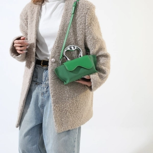 Detail of trendy bright green handbag with metallic silver handle and chic suede texture
