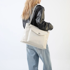 Détail d'un grand sac cabas blanc crème avec texture plissée et anses en chaîne métal