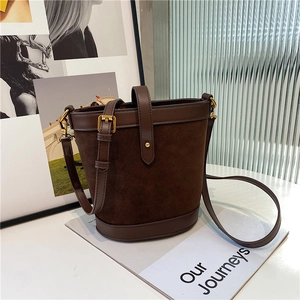 Detail of dark brown bucket bag featuring contrast stitching and golden hardware