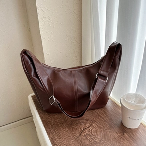 Detail view of the chocolate brown PU leather texture and silver buckle on the crossbody bag