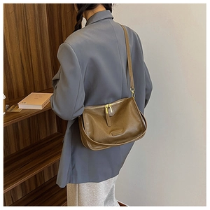 Close-up of brown leather crossbody bag featuring gold zipper and adjustable shoulder strap