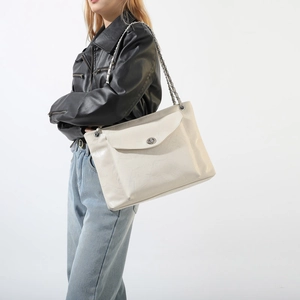 Détail d'un sac à bandoulière beige avec fermoir métallique et texture cuir grainé